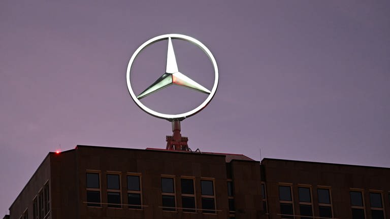 Ein beleuchteter Mercedes-Stern, das Marken-Logo der Automarke Mercedes-Benz, dreht sich auf der ehemaligen Zentrale des Automobilkonzerns.